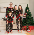 Family wearing matching Christmas pyjamas with plaid and cartoon prints, including parents, children and dog