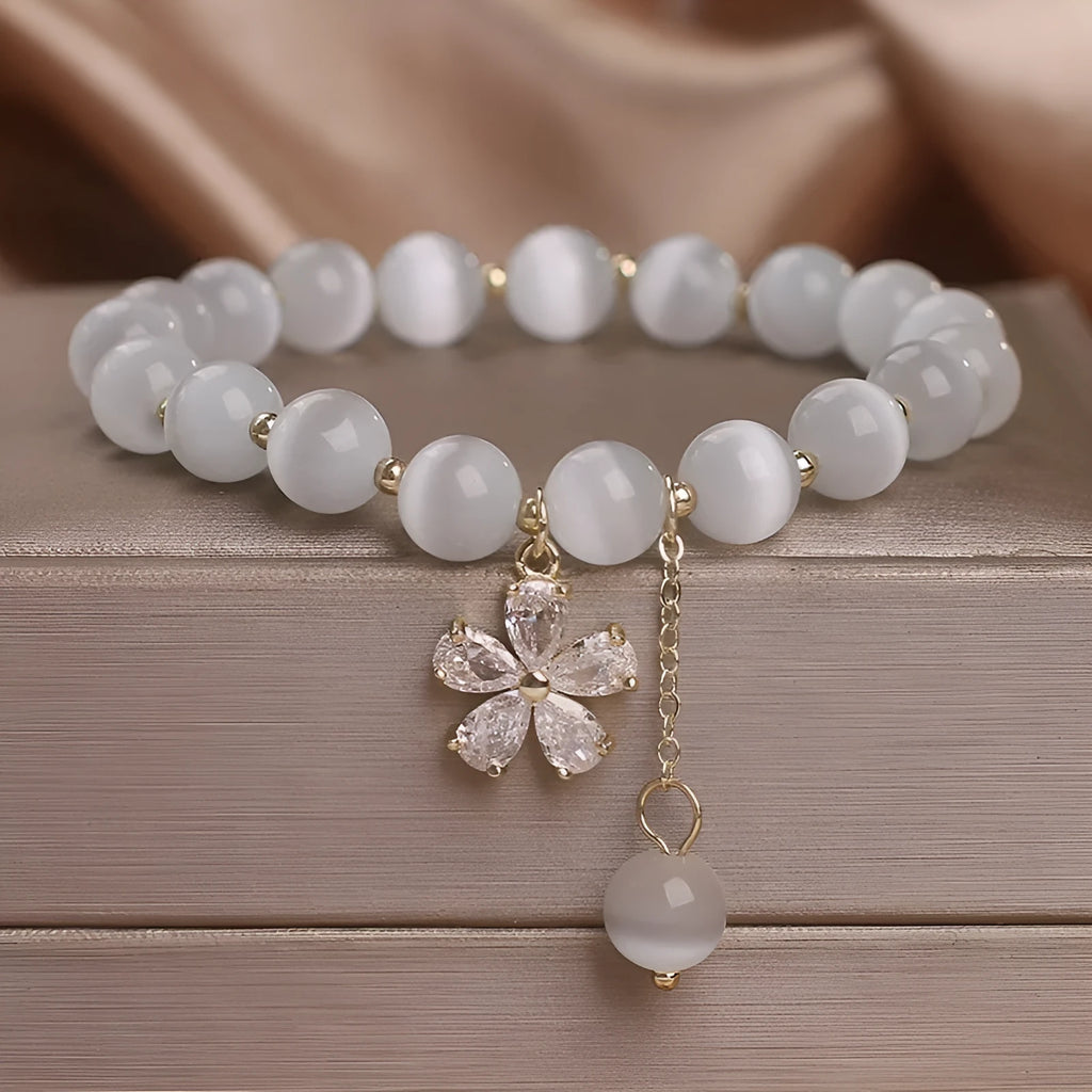 Women's white cat's eye crystal bracelet with flower tassel detailing and safety buckle pendant