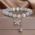 Women's white cat's eye crystal bracelet with flower tassel detailing and safety buckle pendant