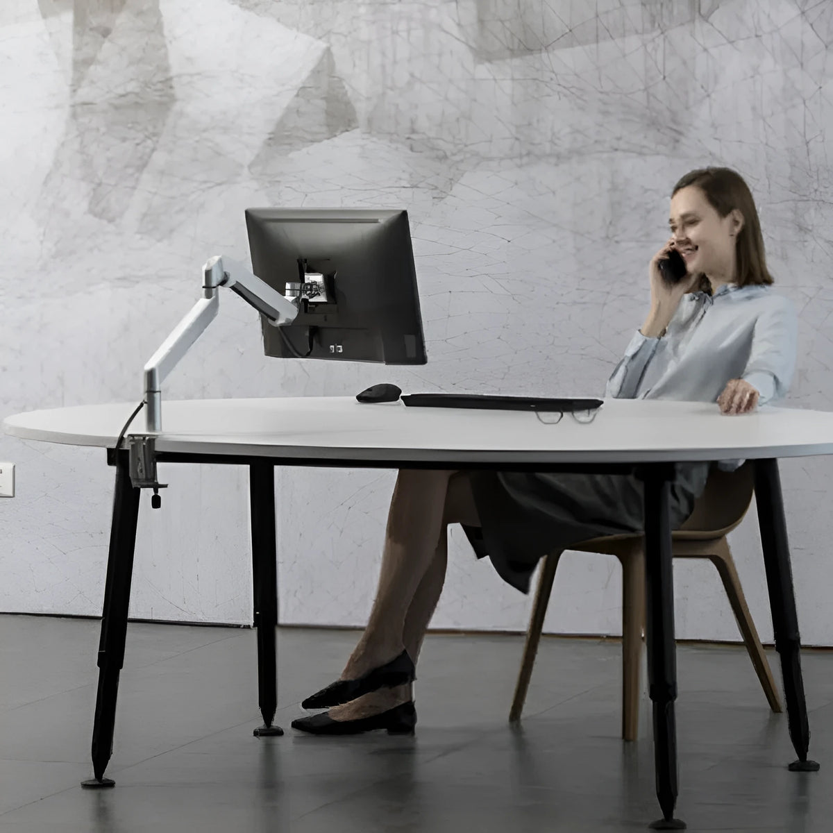 Black aluminium Free Hover adjustable laptop stand mounted on a desk edge, holding a silver notebook.
