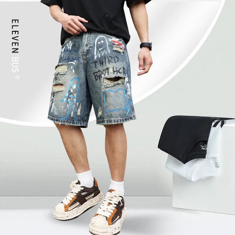 Blue men's denim shorts with ripped knees and graffiti-style print, featuring a straight leg and zipper fly.
