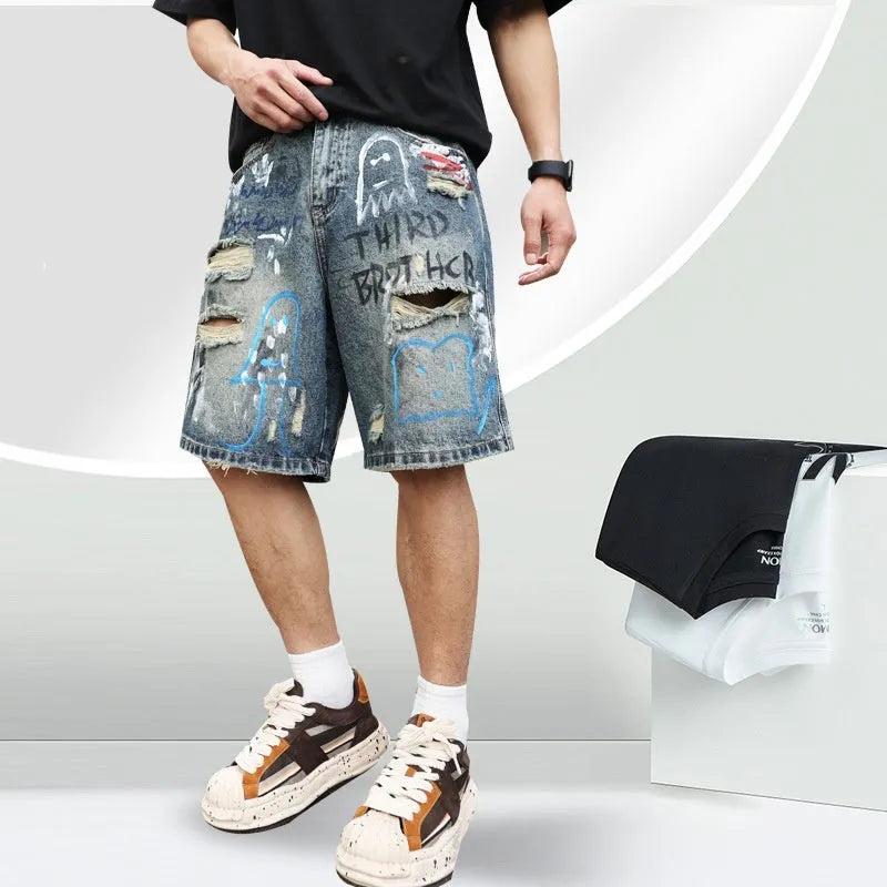 Blue men's denim shorts with ripped knees and graffiti-style print, featuring a straight leg and zipper fly.