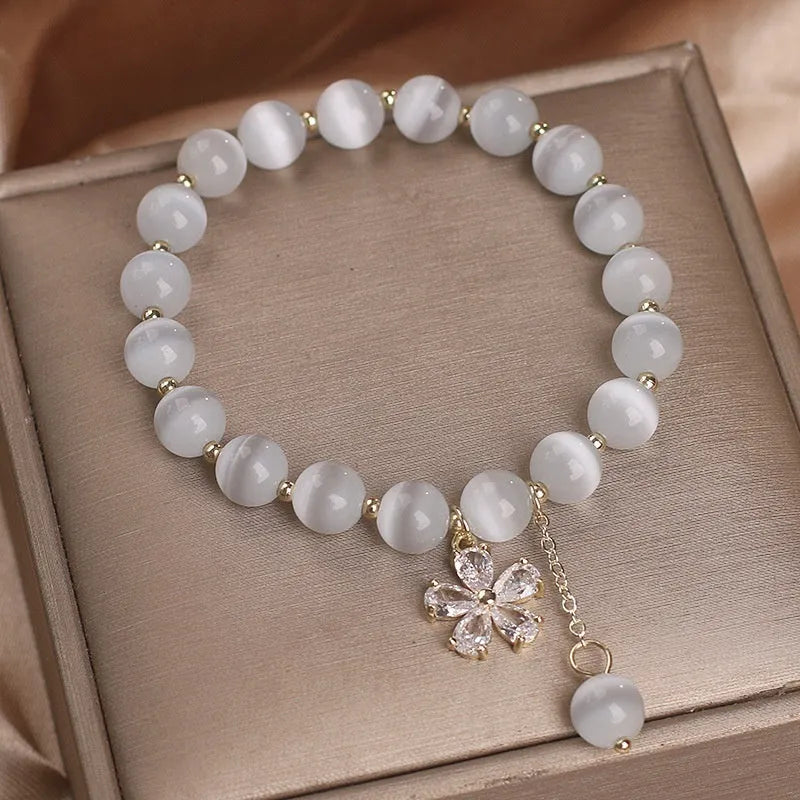 Women's white cat's eye crystal bracelet with flower tassel detailing and safety buckle pendant