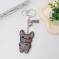 Close-up of a caramel-coloured cartoon dog rhinestone keychain pendant on a keyring.