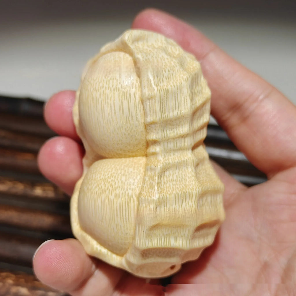 Solid natural bamboo carving peanut ornament on a neutral background