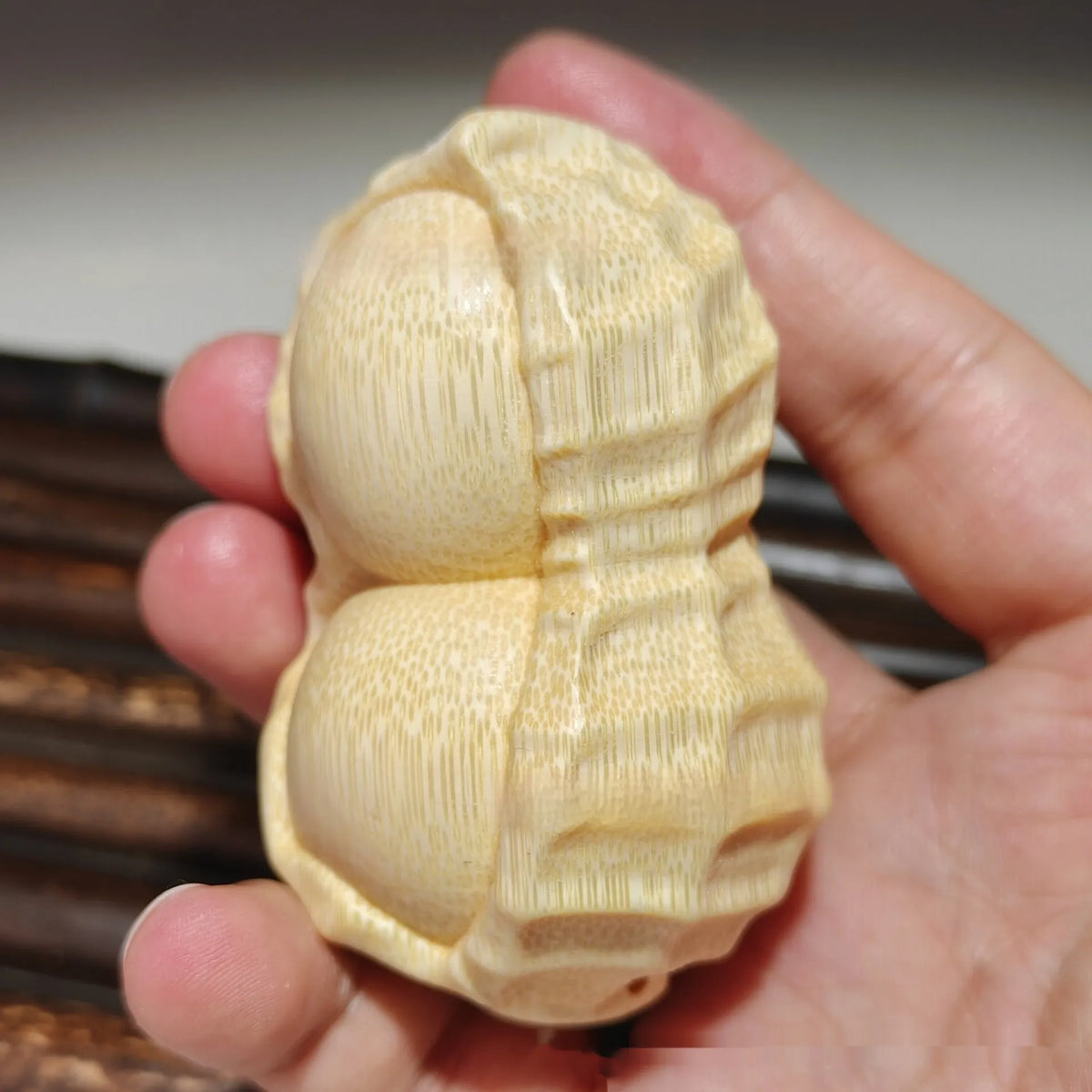 Solid natural bamboo carving peanut ornament on a neutral background