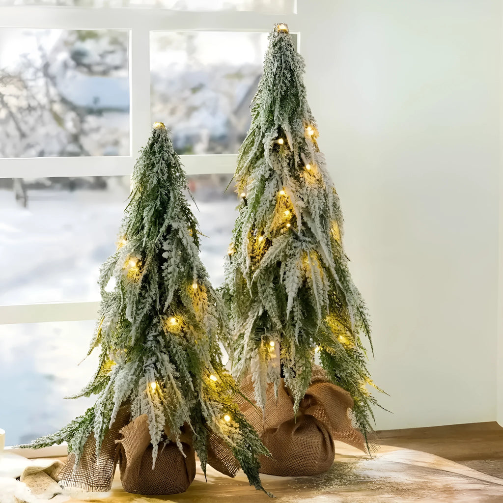 Small white artificial Christmas tree with built-in lights and snow sprayer decoration on desktop