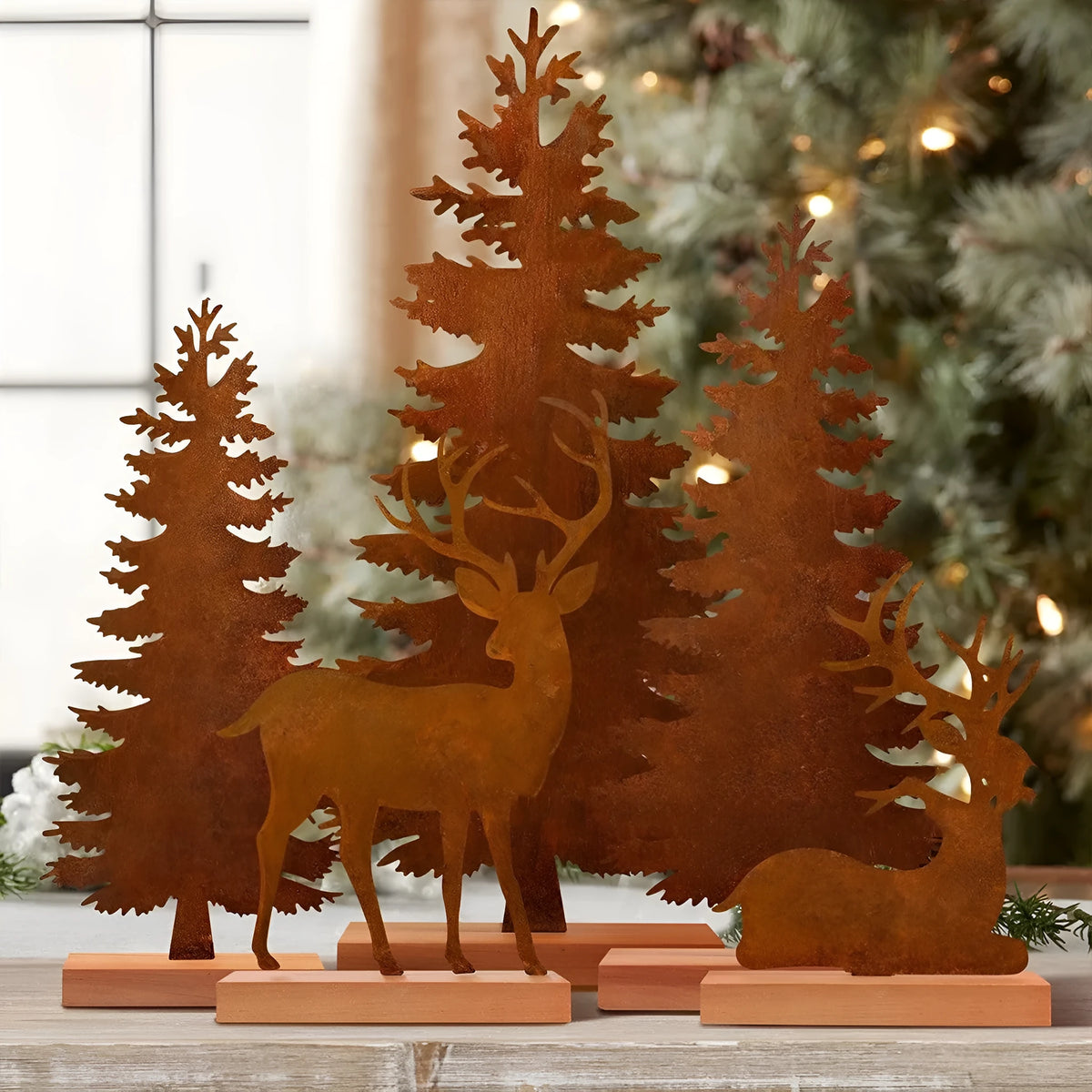 Three rusty metal Christmas decorations featuring elk and trees on a wooden surface