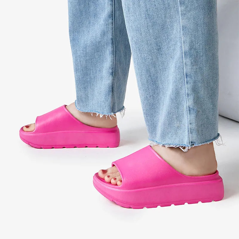 Women's thick-soled beige beach slippers with fish mouth design on a wooden deck.