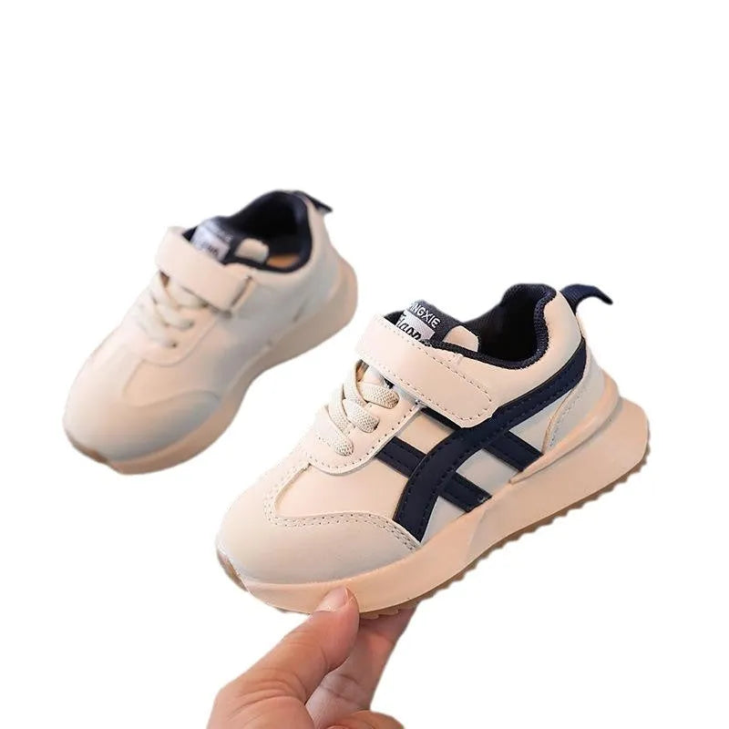 Children's solid colour sneaker with Velcro strap fastening, shown in beige with a rubber sole.