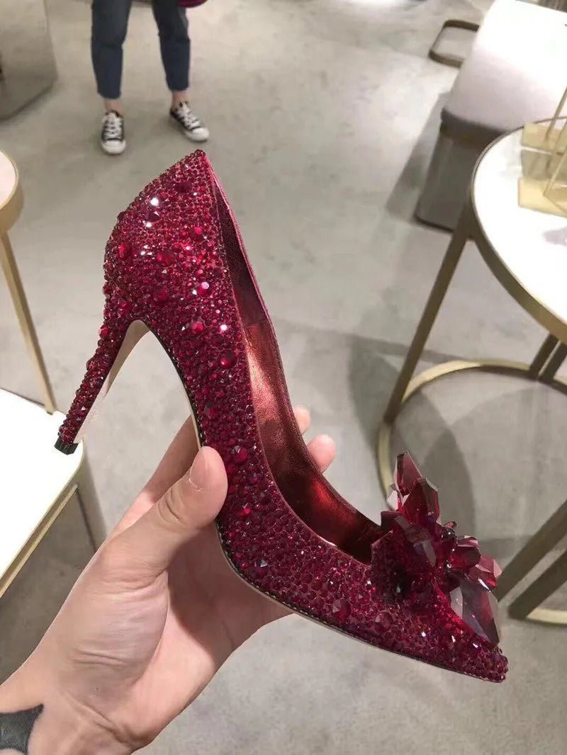 Women's gold stiletto high heels with rhinestone and bow decorations on pointed toe.