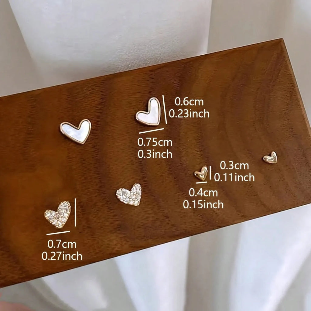 Three pairs of heart-shaped women's earrings in gold, black, black and white, and pink colours