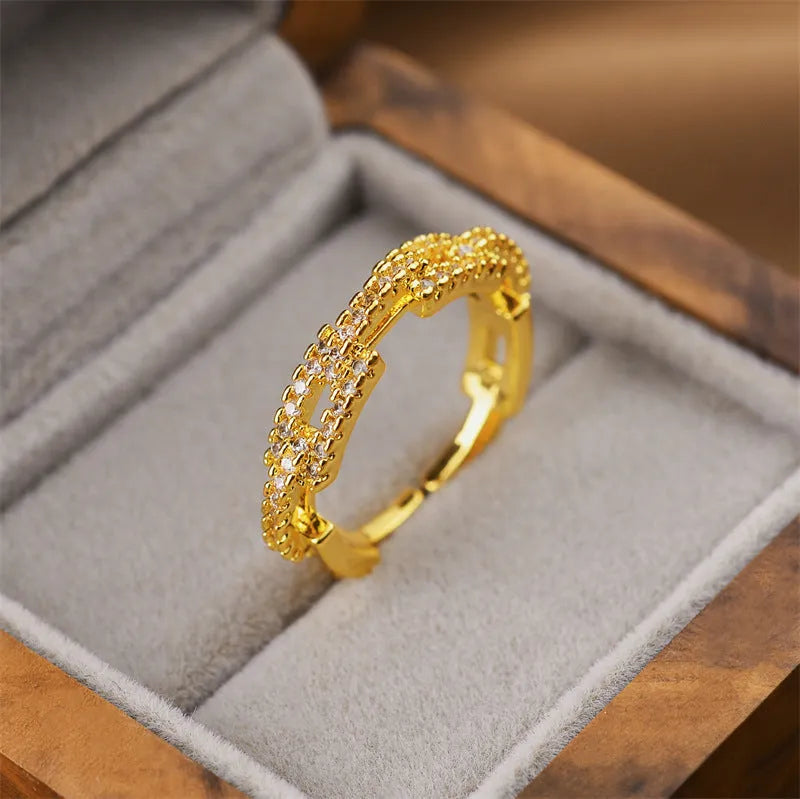 Gold geometric open fashion ring made from electroplated copper on a plain background.