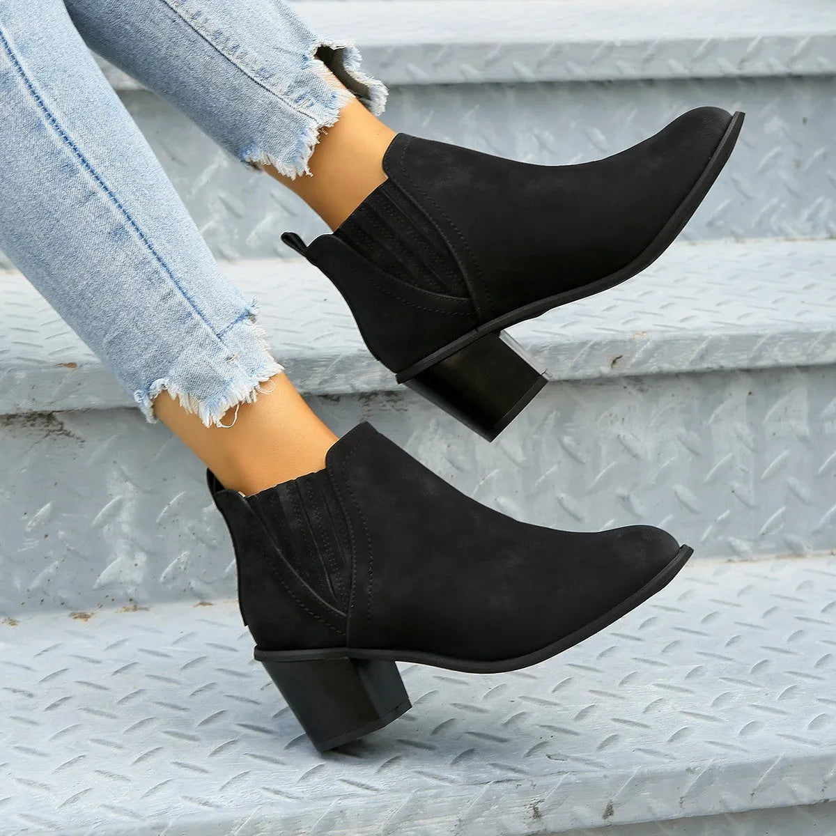Women's black ankle boots with pointed toes and thick square heels on a solid background