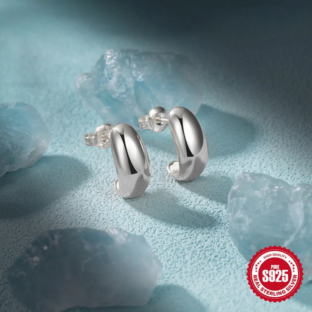 A pair of glossy C-shaped stud earrings in sterling silver, shown in both gold and white gold electroplated finishes.