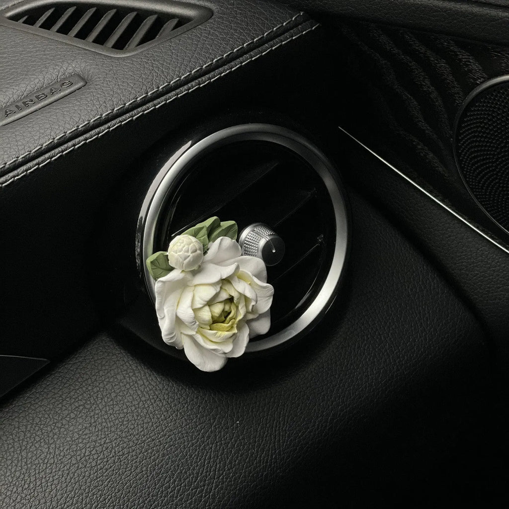 Jasmine car perfume solid air freshener in vent with gypsum base and essential oil bottle.