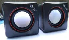Black square USB-powered 2.0 computer speaker on desk with single cable connection