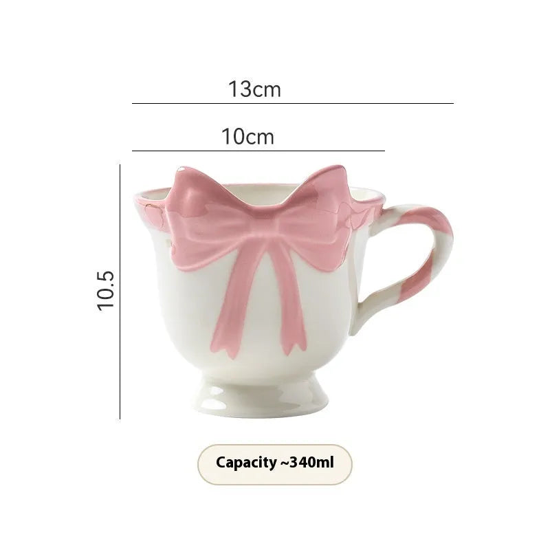 Cute white ceramic mug with a black heart bow design and printed handle ornament.