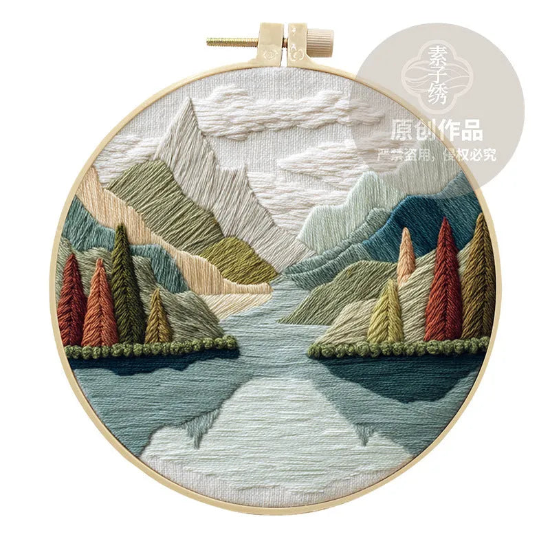 Embroidery DIY kit with cotton landscape fabric, bamboo frame, needles, and thread on wooden table