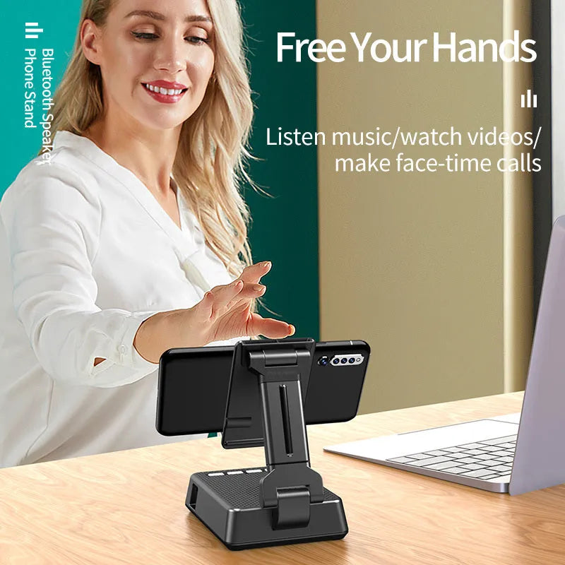 Black mobile phone broadcast stand with integrated Bluetooth speaker and microphone on a desk.