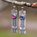 A pair of antique finish red sapphire earrings with a geometric ellipse design in a retro style.