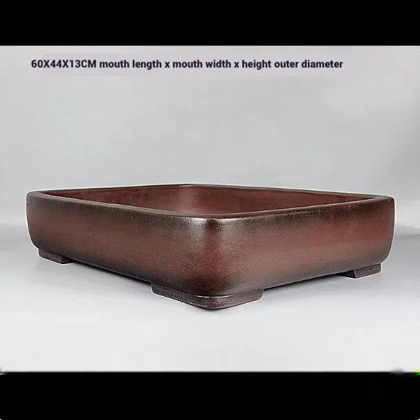 Handmade antique rectangular purple clay flower pot on a wooden surface.