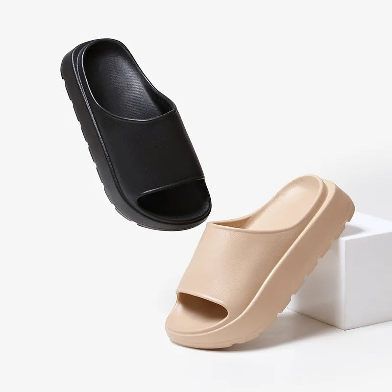 Women's thick-soled beige beach slippers with fish mouth design on a wooden deck.
