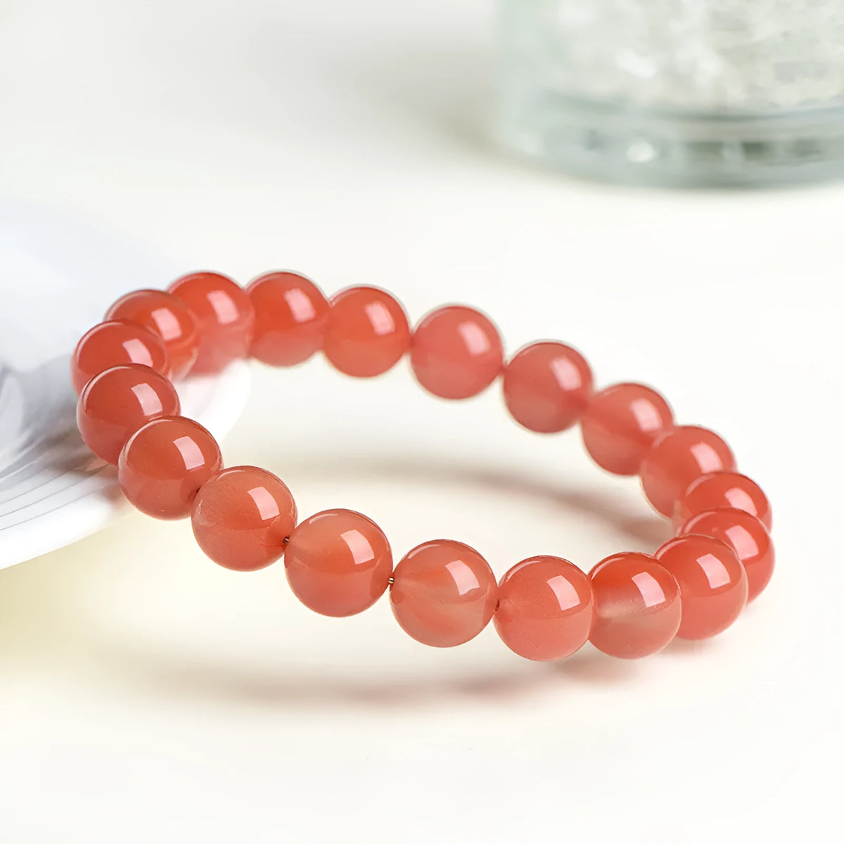Loose polished cherry red agate beads in various sizes for bracelet making on a white surface.