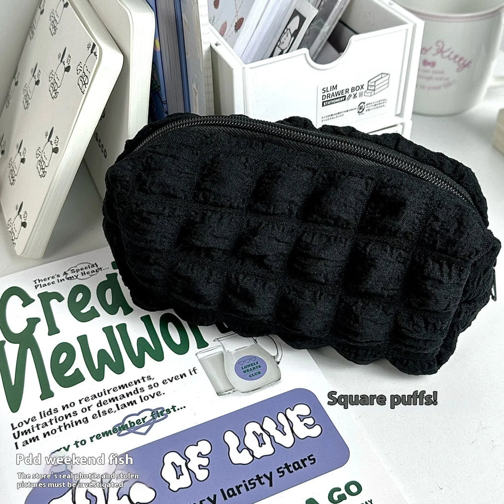 Fabric cream puff style pencil case in polyester material showing beige and black colour options