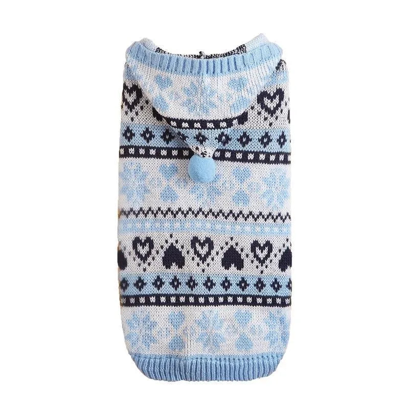 Pink knitted dog sweater with snowflake, heart, and camouflage stripe pattern on a small white dog.