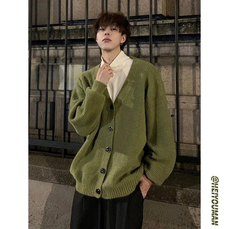 Men's loose fit V-neck cardigan sweater in a solid colour, shown on a casual model.