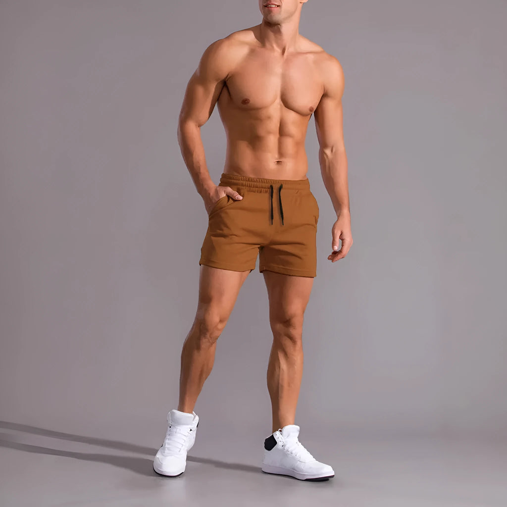 Three pairs of men's solid-colour loose fit shorts with drawstring waists, shown in black, khaki, and light brown.