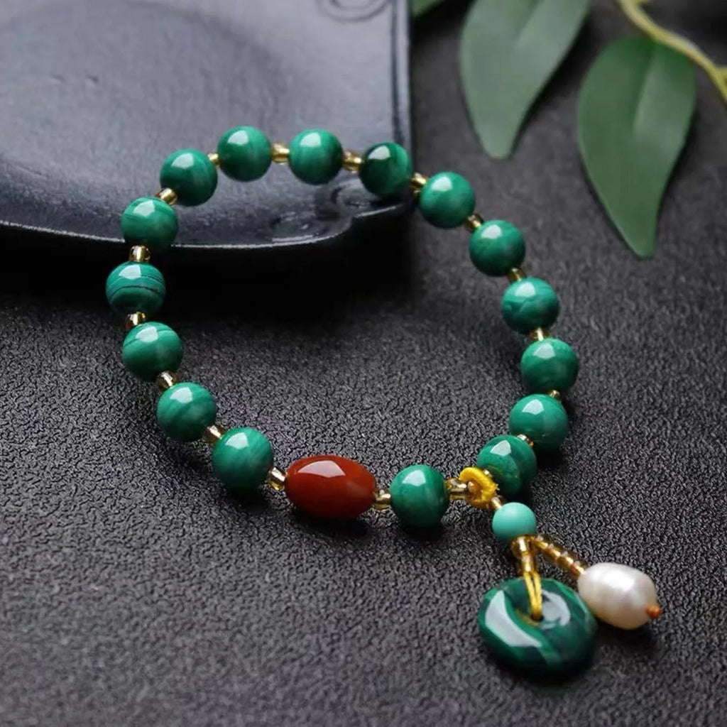 Handmade malachite and red agate bead bracelet with 7-8mm barrel beads on a wrist.