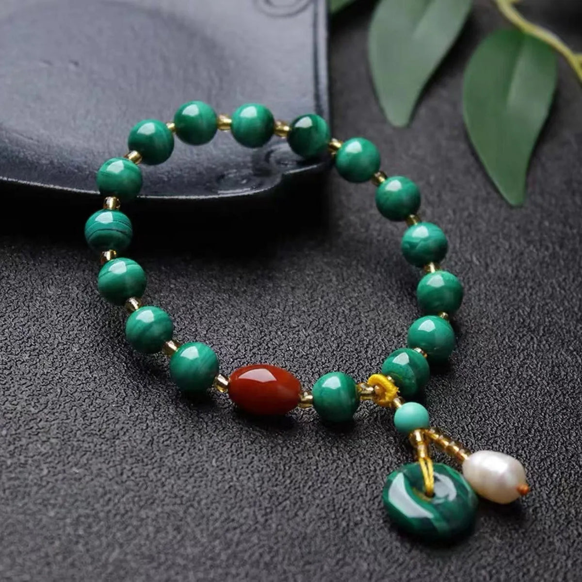 Handmade malachite and red agate bead bracelet with 7-8mm barrel beads on a wrist.