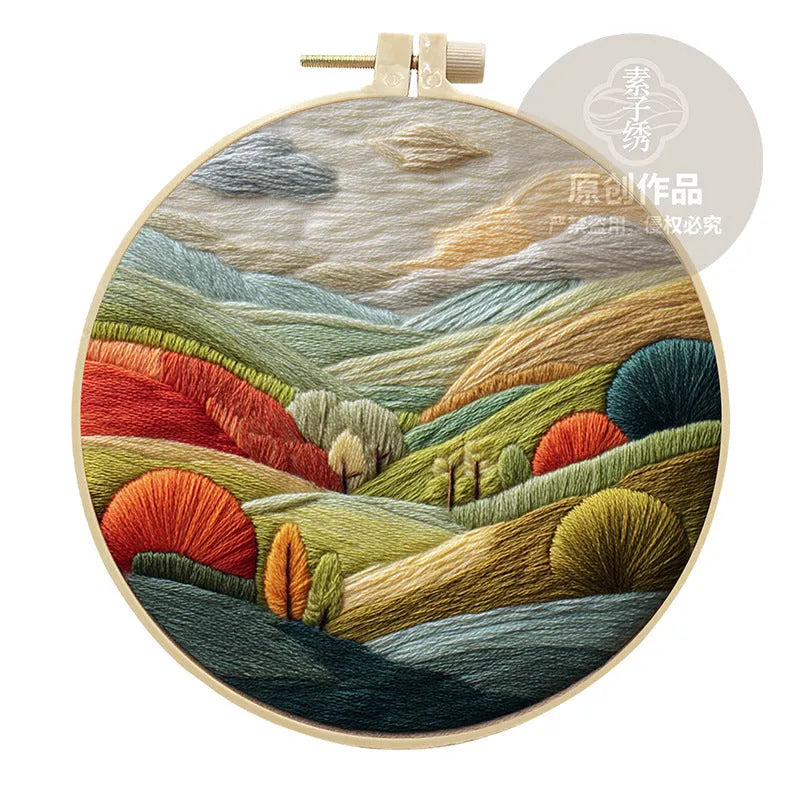 Embroidery DIY kit with cotton landscape fabric, bamboo frame, needles, and thread on wooden table