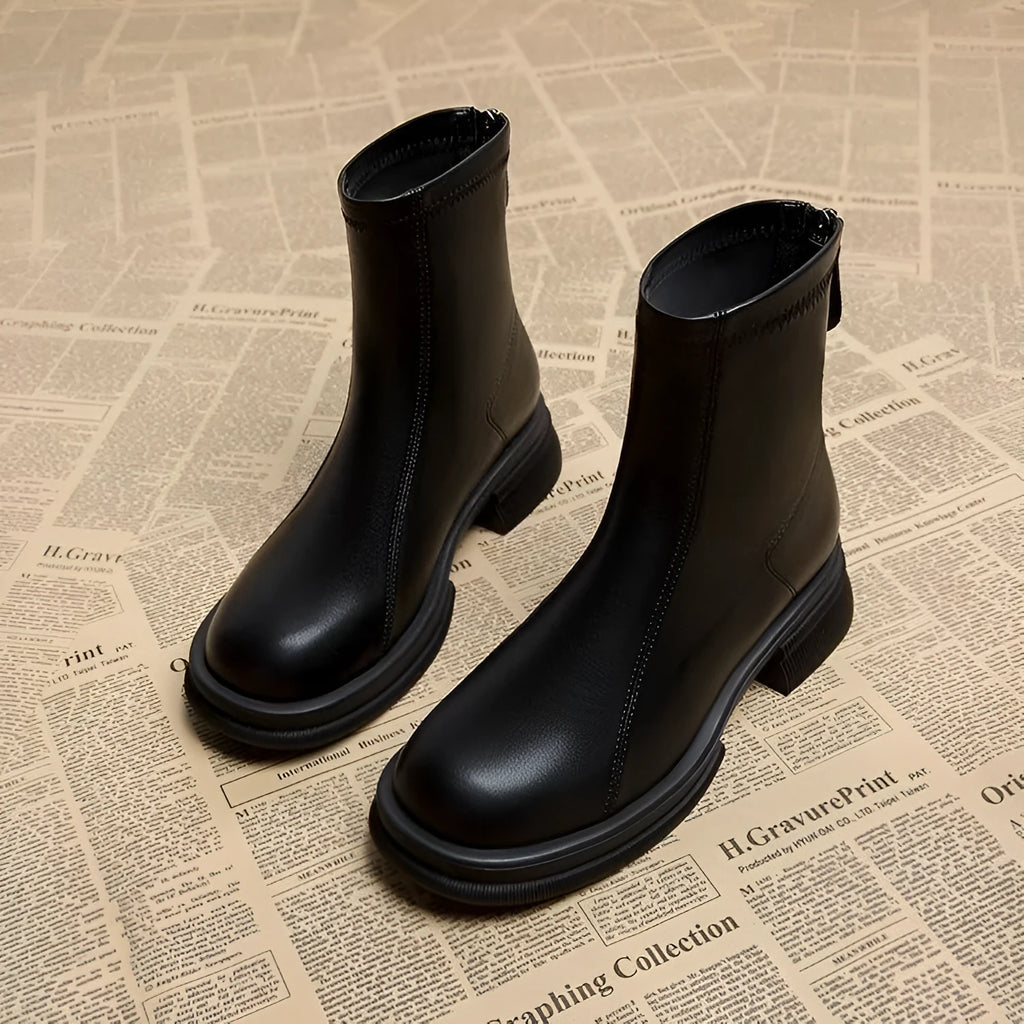 Women's black ankle boots with a thick flat heel, round toe, and back zip fastening.