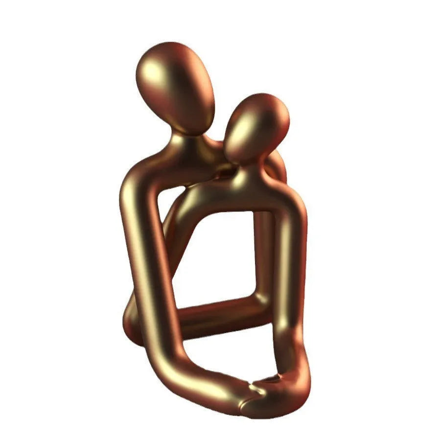 Modern heartwarming couple resin statue in milky white or gold colour on a wooden desk.